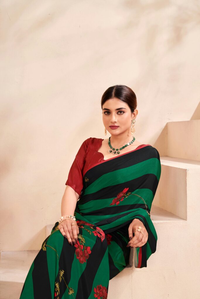 A woman in a stylish green and red saree seated on stairs in Surat, India.