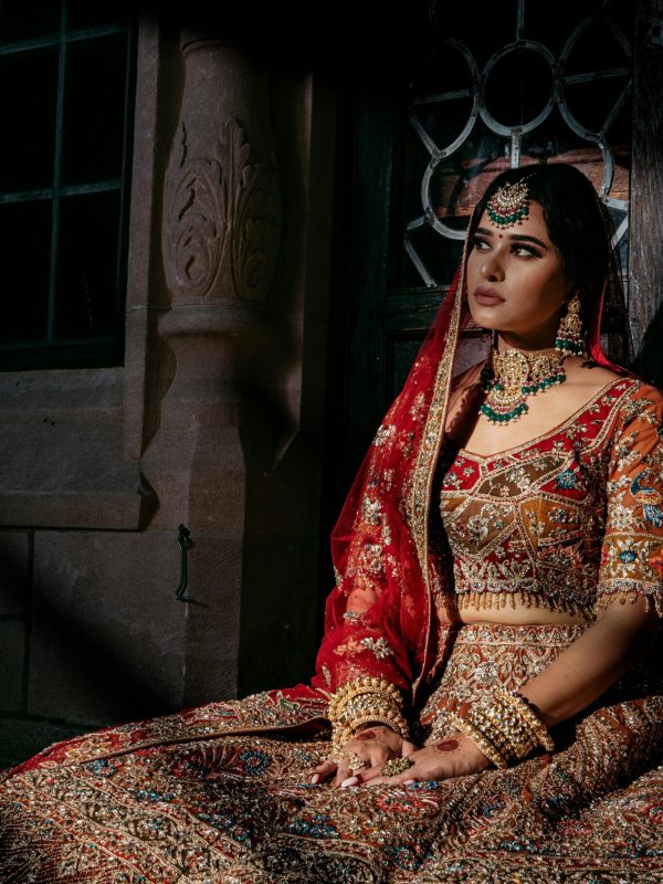 Elegant South Asian bride wearing a red and gold embroidered lehenga.